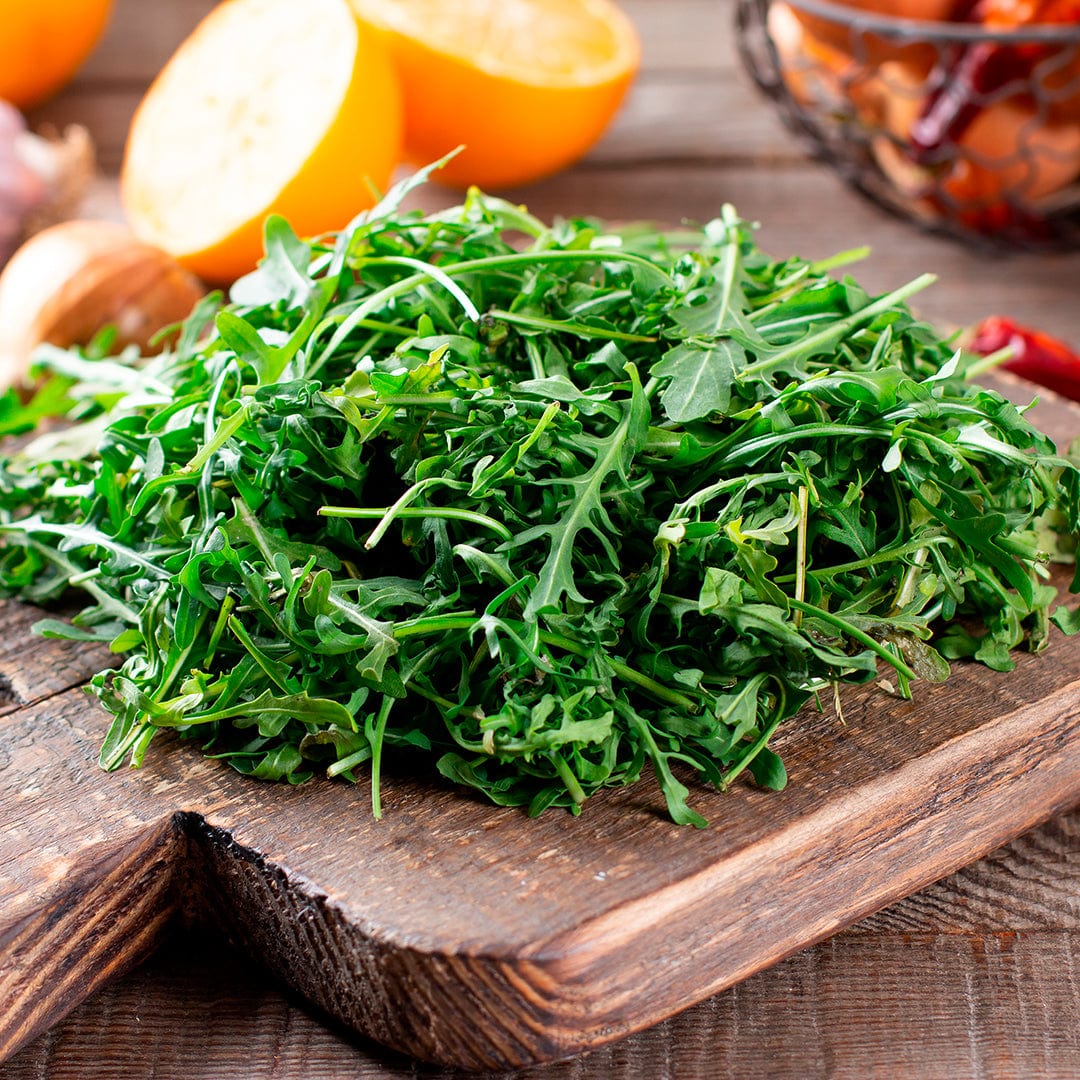Fresh organic arugula leaves piled on a wooden cutting board with lemon halves and spices nearby. - Organic Arugula Seeds — 'Roquette' - Default Title - Back to the Roots