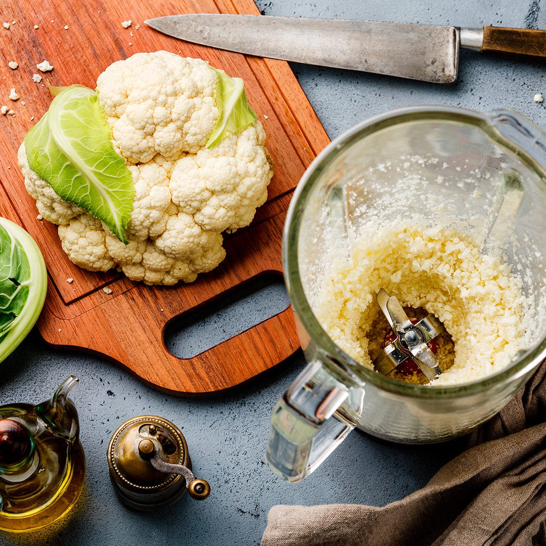 Fresh organic cauliflower head on wooden cutting board next to blender with chopped cauliflower and kitchen knife. - Organic Cauliflower Seeds — 'Snowball Y' - Default Title - Back to the Roots