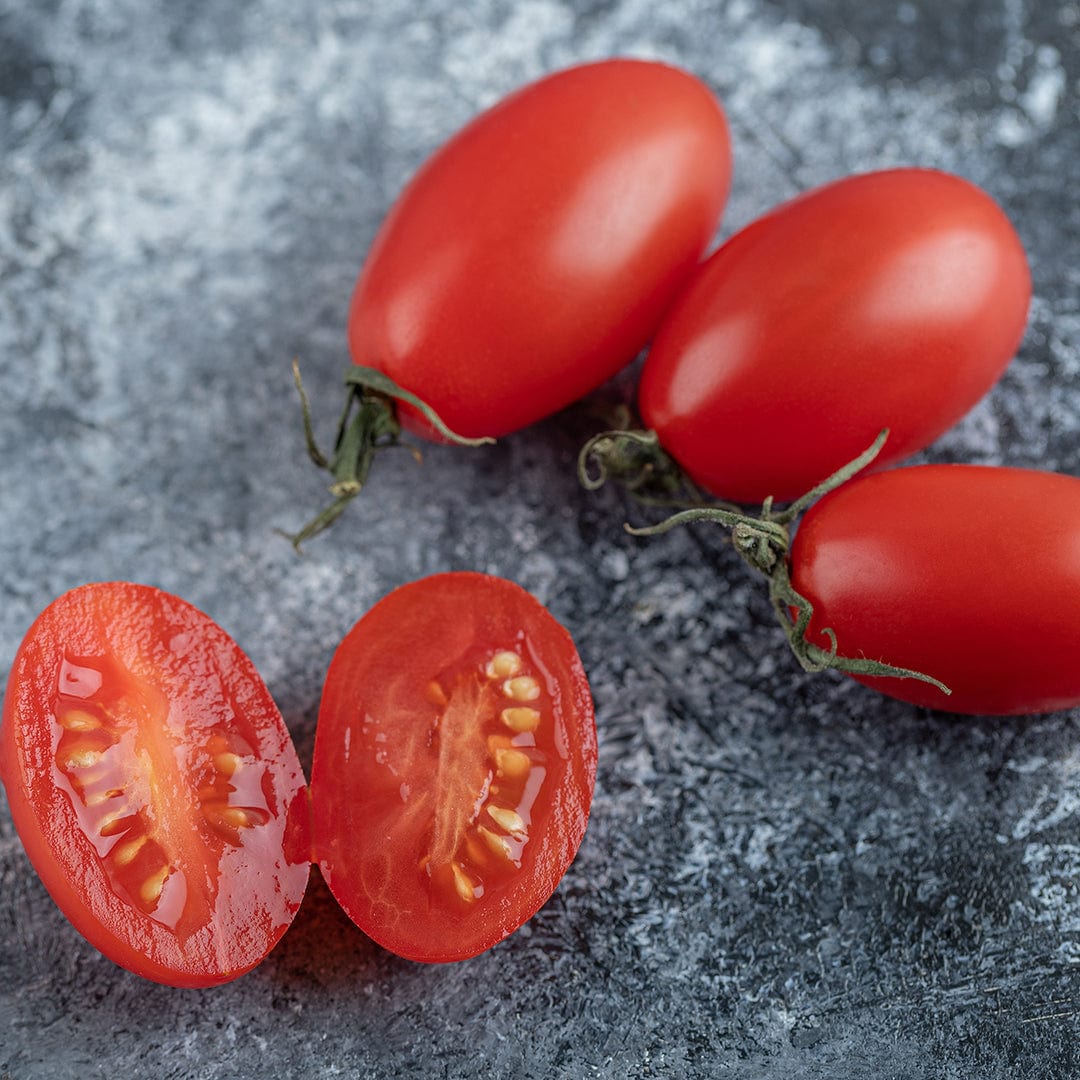Cluster of elongated red Amish Paste tomatoes with one tomato sliced open showing juicy interior and seeds on a textured. - Organic Tomato Seeds — 'Amish Paste' - Default Title - Back to the Roots