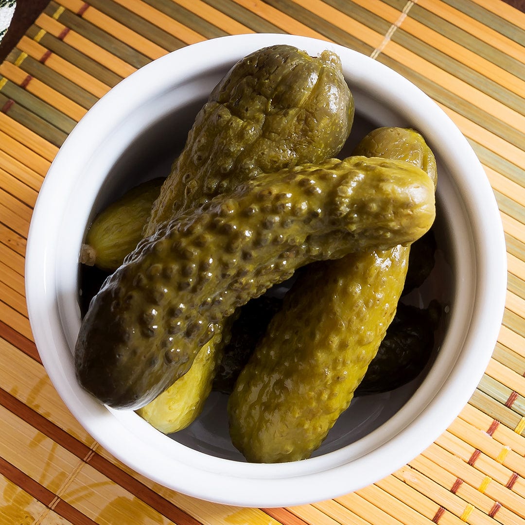 White bowl filled with dark green and yellow pickling cucumbers on a bamboo mat. - Organic Cucumber Seeds — 'Pickling • Sumter' - Default Title - Back to the Roots