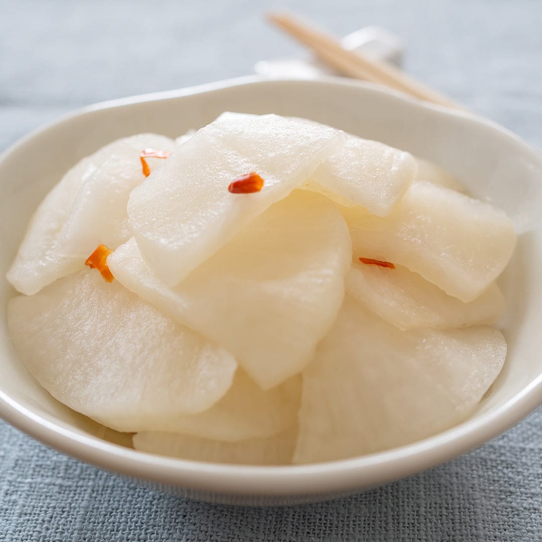 White daikon radish slices in a bowl garnished with small red chili flakes. - Organic Radish Seeds — 'Daikon' - Default Title - Back to the Roots