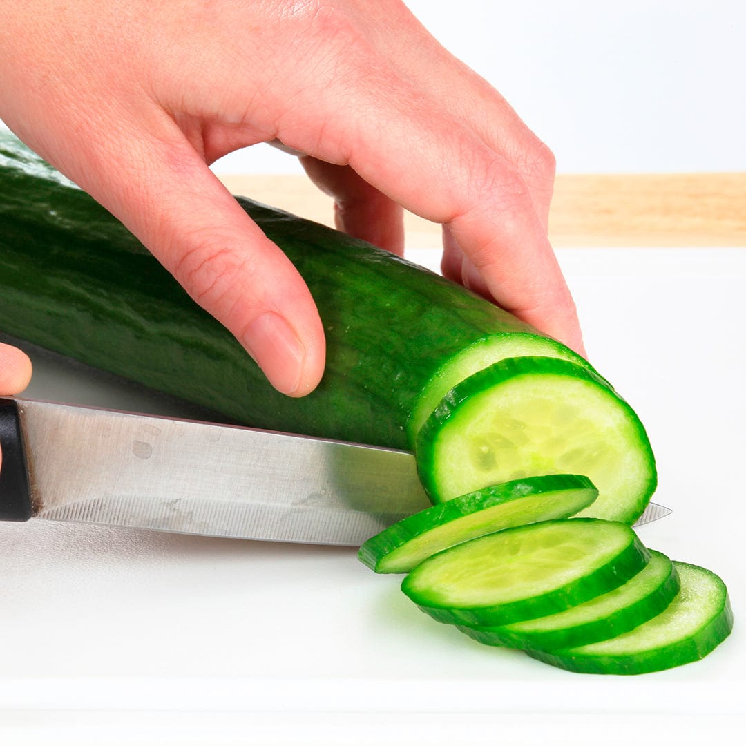 Hand slicing fresh green cucumber on white cutting board with sharp knife. - Organic Cucumber Seeds — 'Slicing • Muncher' - Default Title - Back to the Roots