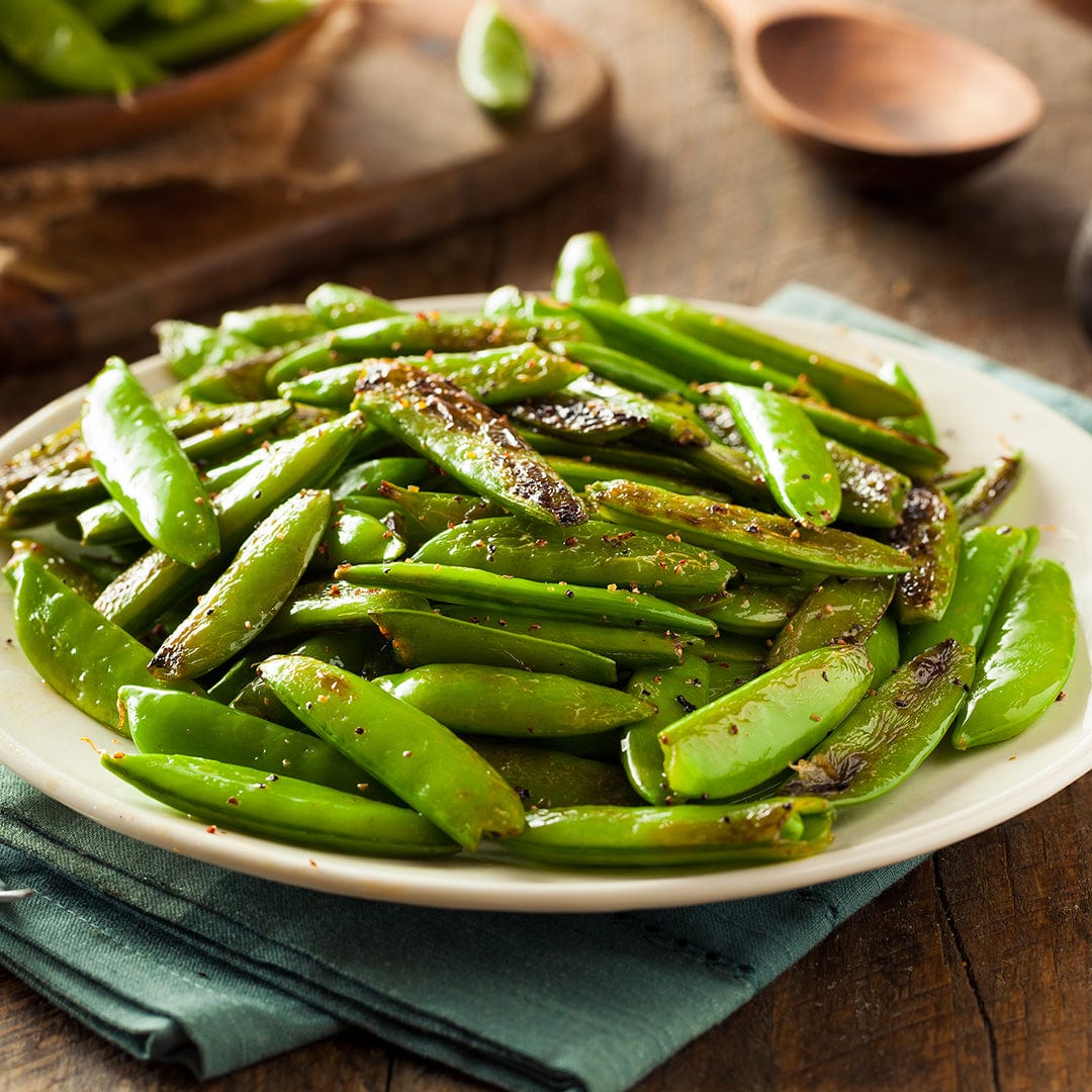 Plate of fresh green sugar snap peas seasoned with cracked black pepper on a wooden table. - Organic Pea Seeds — 'Oregon Snow Sugar Pod II' - Default Title - Back to the Roots