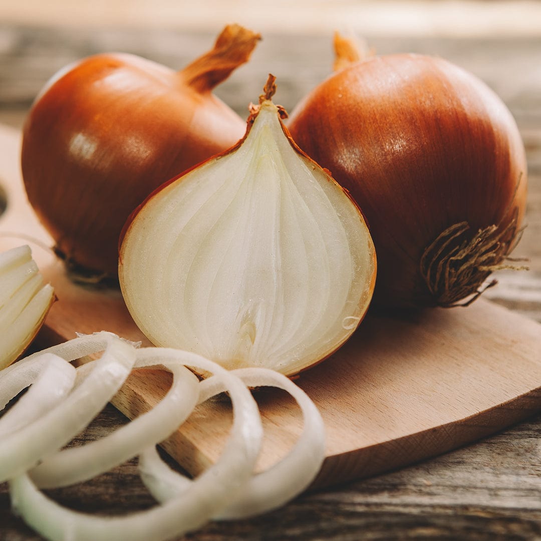 Three 'Yellow Spanish Utah' organic onions by Back to the Roots rest on a wooden surface, one sliced open with onion rings in front—perfect inspiration for growing your own with Organic Onion Seeds from Back to the Roots.