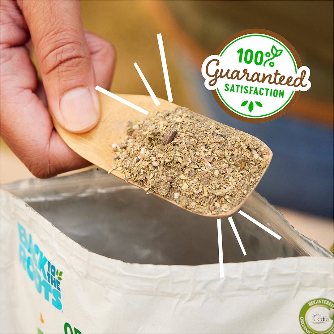 A hand holds a wooden scoop of dry Natural & Organic ALL-PURPOSE Plant Food above an open Back to the Roots bag, with a "100% Guaranteed Satisfaction" graphic in the corner.