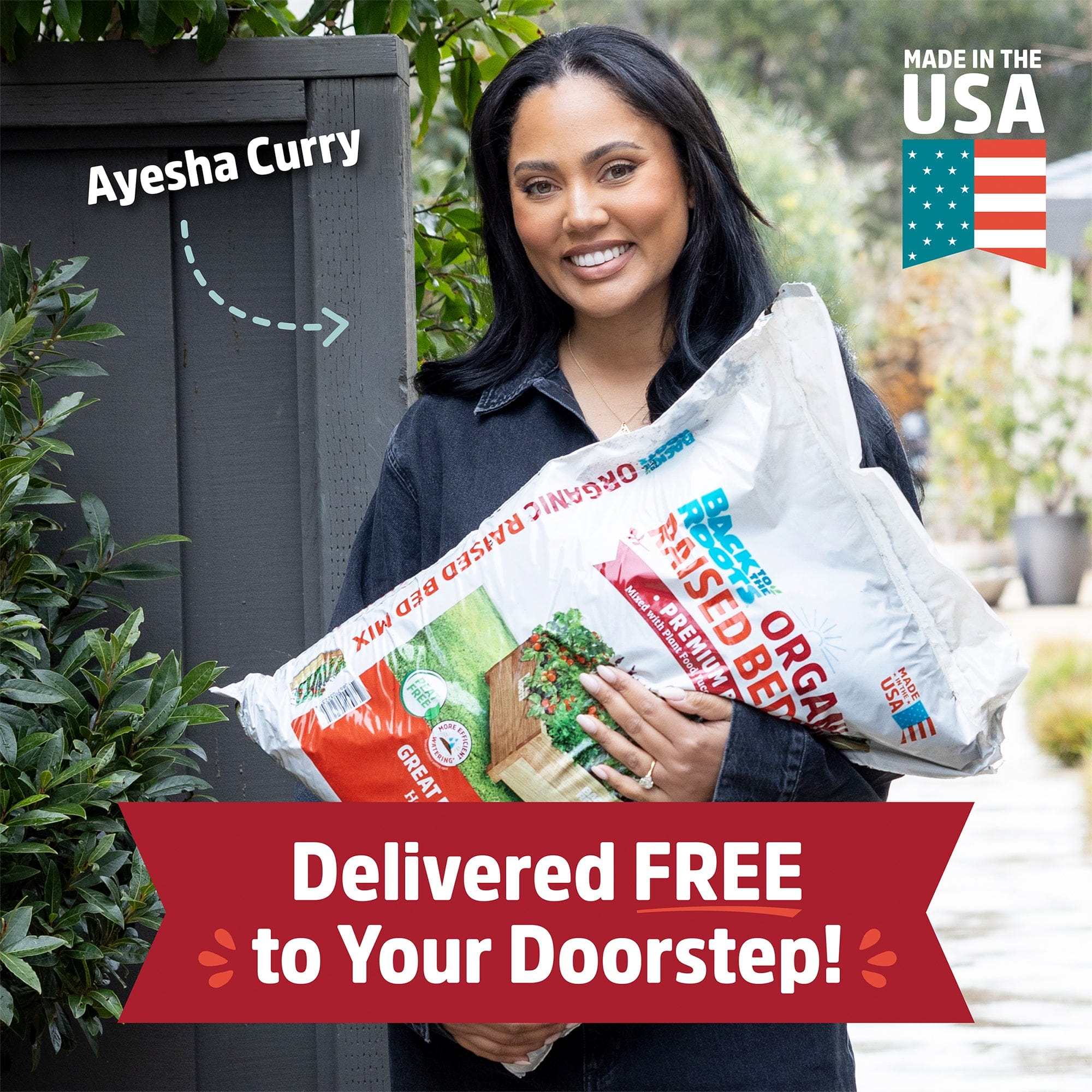 A woman smiles while holding a Back to the Roots Organic Premium Blend Raised Bed Mix 1 cu.ft. – 10 Pack in a garden. Text reads "Delivered FREE to Your Doorstep!", with "Made in the USA" and "Ayesha Curry" labels.