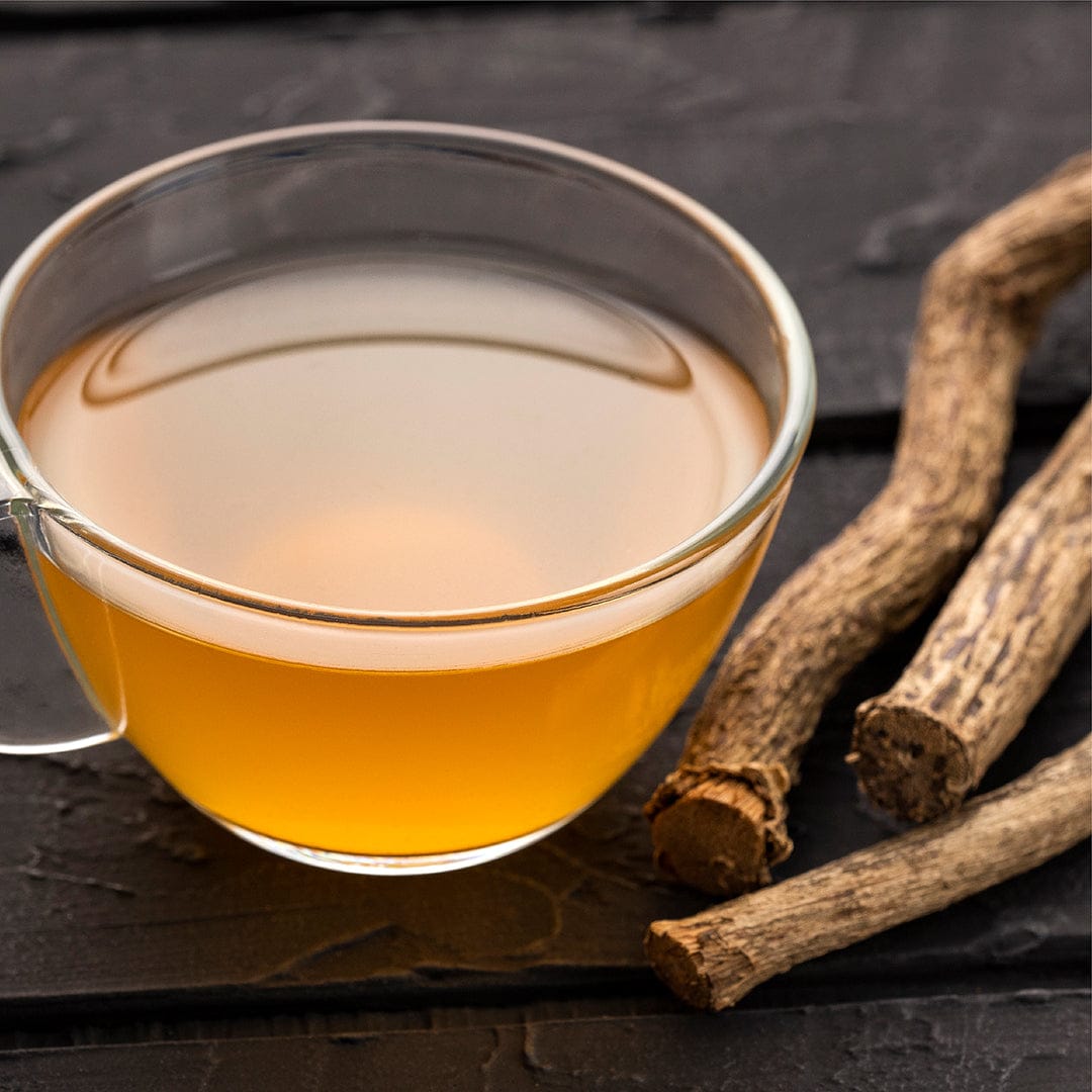 Clear glass cup with amber valerian tea next to rough, brown valerian root sticks on dark wooden surface. - Organic Valerian Seeds - Default Title - Back to the Roots