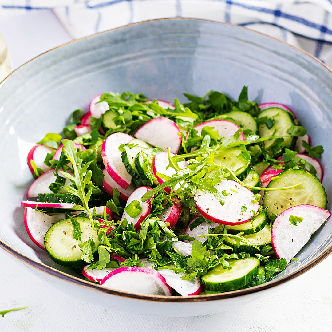 Fresh radish and cucumber salad with leafy greens in a light blue bowl on a checkered cloth. - Winter Veggies Organic Seed Bundle - Default Title - Back to the Roots