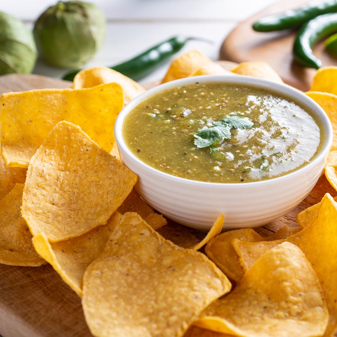 White bowl filled with green tomatillo salsa topped with cilantro surrounded by golden tortilla chips on wooden surface. - Organic Tomatillo Seeds — 'Green Husk' - Default Title - Back to the Roots