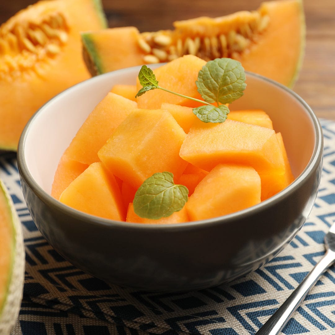 Black bowl filled with bright orange cantaloupe cubes garnished with small green leaves. - Organic Cantaloupe Seeds — 'Honey Rock' - Default Title - Back to the Roots
