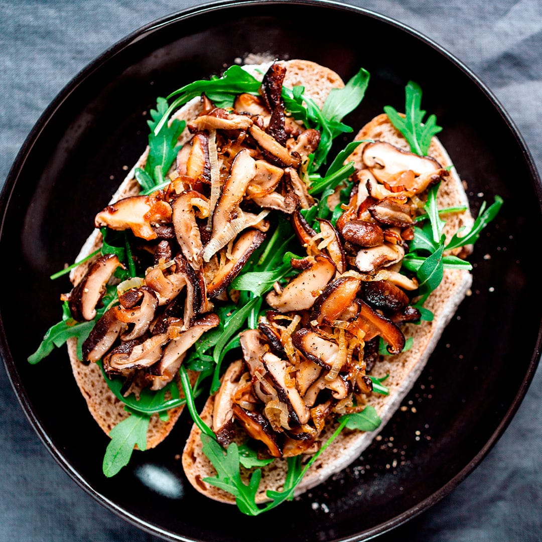 Toasted bread slices topped with sautéed shiitake mushrooms and fresh green arugula on a black plate. - Organic Shiitake Mushroom Kit (START GROWING RIGHT AWAY) - Default Title - Back to the Roots